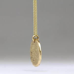 May include: A gold chain necklace with a round, textured pendant.