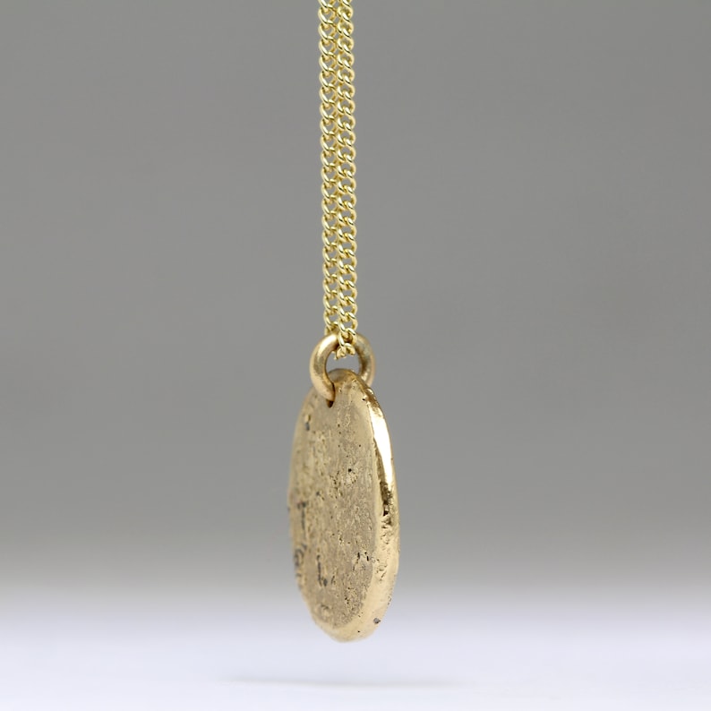 May include: A gold chain necklace with a round, textured pendant.
