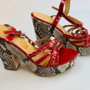 May include: Red platform sandals with a snakeskin print heel and braided straps.