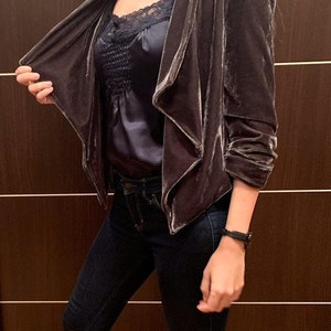 May include: A grey velvet blazer with a draped collar and long sleeves. The blazer is open at the front, revealing a black satin camisole with lace trim.