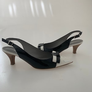 May include: Black and white patent leather slingback heels with a bow detail on the toe.