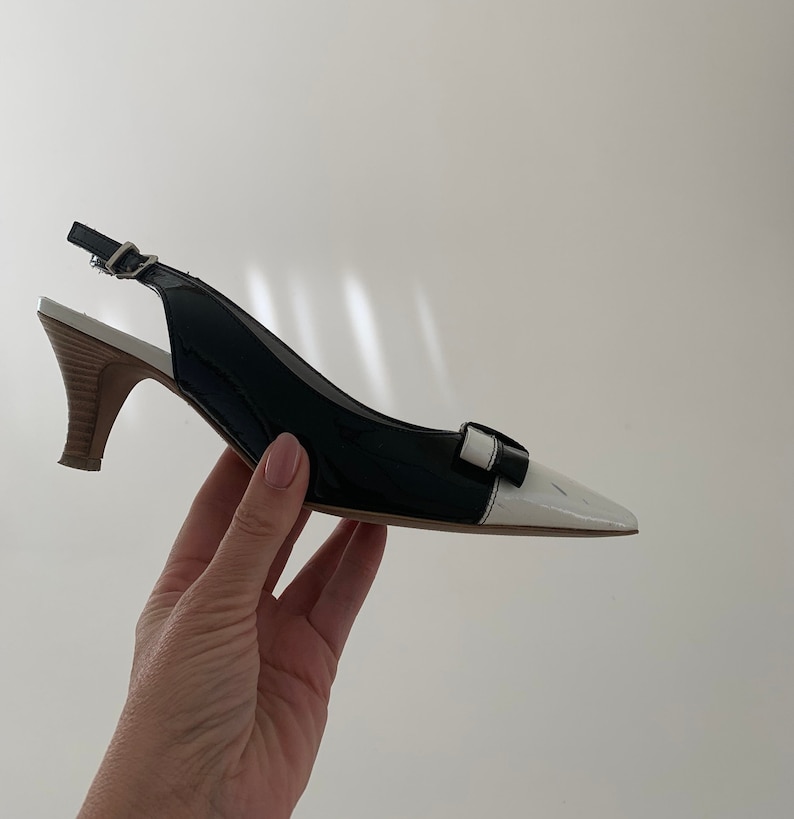 May include: Black and white slingback heels with a small heel and a white toe.