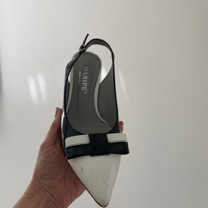 May include: Black and white slingback heels with a bow detail. The heels are made by Marip&eacute;, Made in Italy.