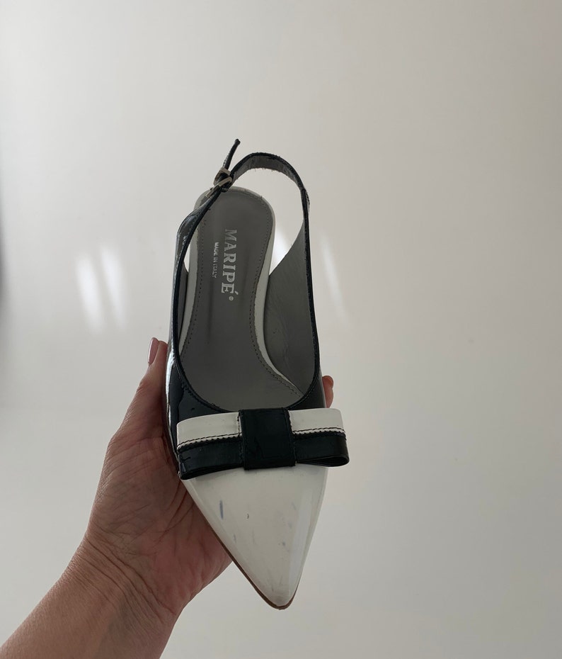May include: Black and white slingback heels with a bow detail. The heels are made by Marip&eacute;, Made in Italy.