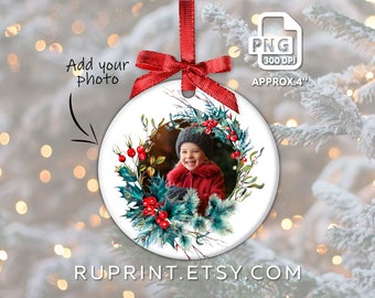May include: A white ceramic Christmas ornament with a red ribbon. The ornament features a photo surrounded by a watercolor wreath of holly, berries, and pine. The text "Add your photo" is visible.