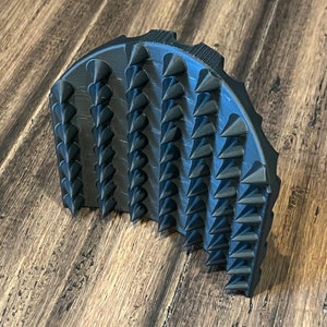 May include: A black rubber shoe traction device with a semi-circular shape and rows of sharp spikes.