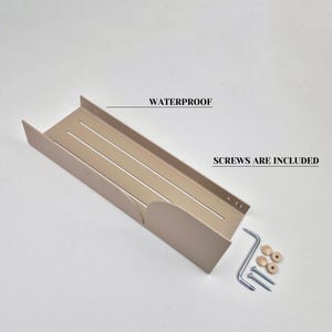 May include: A beige metal shelf with three horizontal slots and rounded edges. The shelf is designed to be mounted on a wall. The text "WATERPROOF" and "SCREWS ARE INCLUDED" are visible in the image. The shelf comes with two screws and two plastic anchors.