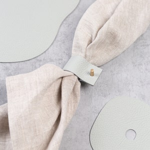 Light grey leather napkin holder with linen napkin
