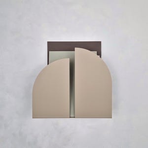 Op de afbeelding: Abstract geometrisch kunstwerk met een gelaagde compositie. Het kunstwerk toont een halfronde vorm in een neutraal beige, verdeeld door een verticale lijn. Een rechthoekige donkerbruine vorm vormt de achtergrond, met een lichtgroene rechthoek in het midden.