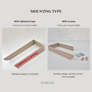 May include: A beige U-shaped wall mount with two installation options: adhesive tape for up to 0.3 kg or screws for up to 2 kg. The image displays the mount with red adhesive strips, and separately with metal screws, wall plugs, and covers. Text reads MOUNTING TYPE, With adhesive tape, With screws, and NAMUOS.