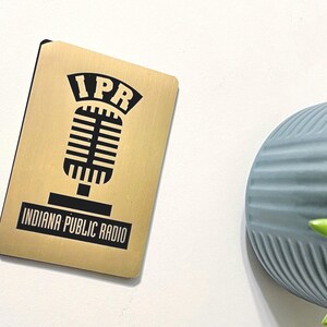 May include: A gold metal plaque with a black microphone graphic and the text "IPR Indiana Public Radio".