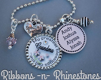 May include: A silver necklace with multiple charms. The charms include a heart with the text "Special Grandma", a round charm with the text "My greatest blessings call me Grandma", a round charm with the text "Andy Joshua Alyssa Jonah", and a black and white striped bead.