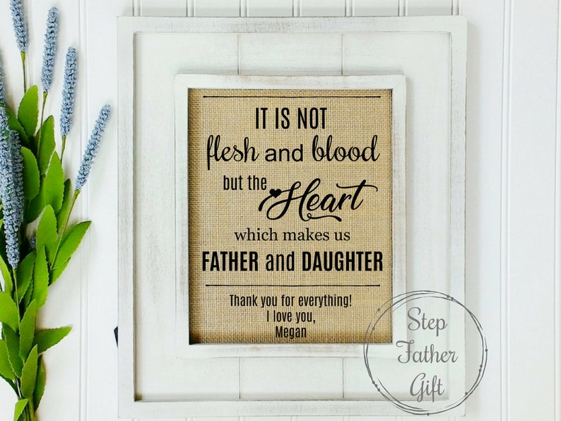 May include: A white framed burlap sign with the text "IT IS NOT flesh and blood but the Heart which makes us FATHER and DAUGHTER" and a small heart symbol. The sign also includes the text "Thank you for everything! I love you, Megan" and a circle with the text "Step Father Gift".