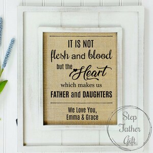 May include: White framed burlap sign with black text that reads "It is not flesh and blood but the Heart which makes us Father and Daughters. We Love You, Emma & Grace." The bottom right corner of the sign has a circle with the text "Step Father Gift".
