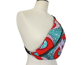 May include: A colorful fanny pack with a vibrant pattern of red, teal, and white swirls. The bag features a black zipper and strap, and is displayed on a mannequin. The bag has a label that says "Jenny Patsy".