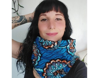 May include: A blue and orange patterned neck gaiter. The gaiter features a vibrant floral design on a blue background. The fabric appears soft and comfortable, suitable for various weather conditions. The product is designed to be worn around the neck.