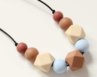 May include: A necklace made of silicone beads in shades of brown, beige, and blue. The beads are in a variety of shapes, including round and geometric.