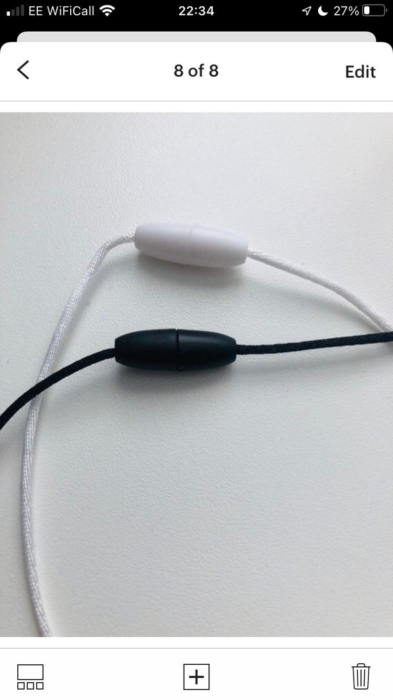 May include: A white cord with a white plastic toggle and a black cord with a black plastic toggle.