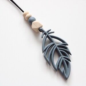 May include: A gray silicone teething necklace with a feather pendant and wooden beads. The necklace is a great way to help soothe babies and toddlers.