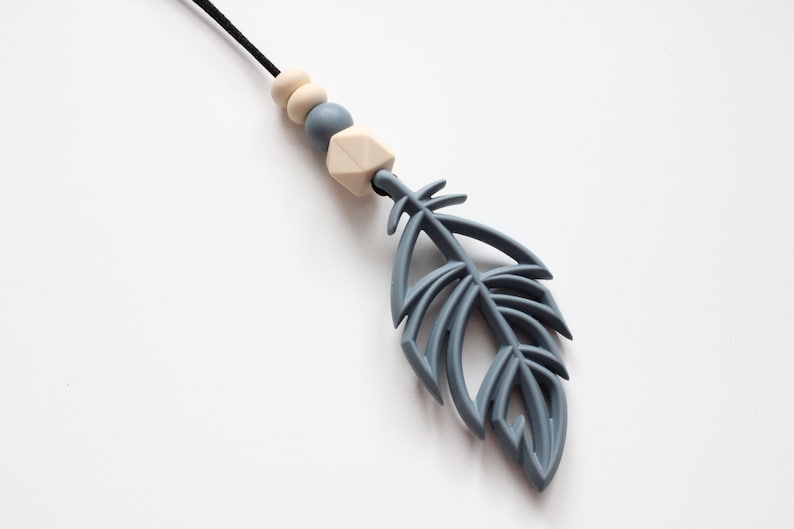 May include: A gray silicone teething necklace with a feather pendant and wooden beads. The necklace is a great way to help soothe babies and toddlers.