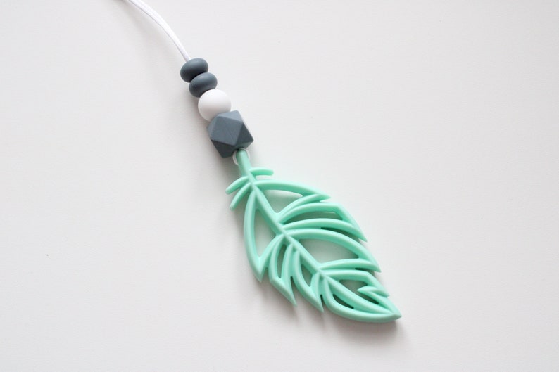 May include: A mint green silicone feather pendant with a white and gray silicone bead necklace.