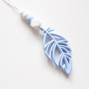 May include: A light blue silicone baby teether with a feather shape and white beads.