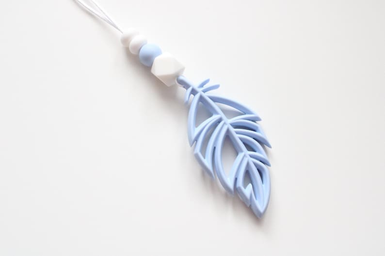 May include: A light blue silicone baby teether with a feather shape and white beads.