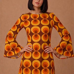 Mini vestido mod gogo estampado op art con mangas acampanadas. Mini estampado geométrico color naranja, amarillo y café estilo 60s y 70s.