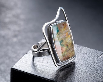 Puede incluir: Un anillo de plata con una piedra rectangular colorida engastada en un diseño abstracto único.