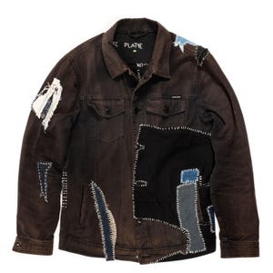 Può includere: Una giacca di jeans marrone scuro con toppe di denim di diversi colori cucite sopra. La giacca ha un'etichetta che dice "PLATIME" sul lato sinistro del colletto.