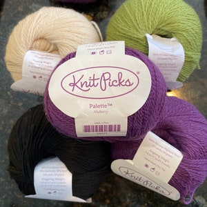May include: Five balls of yarn in different colors, including black, white, green, purple, and a deep purple. The yarn is labeled "Knit Picks Palette™ Mulberry" and "Made in Peru".