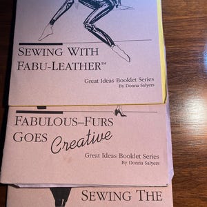 May include: Three vintage sewing pattern books with illustrations of women wearing leather, fur, and fake fur garments. The books are titled "Sewing with Fabu-Leather", "Fabulous-Furs Goes Creative", and "Sewing the Fabulous Fakes".
