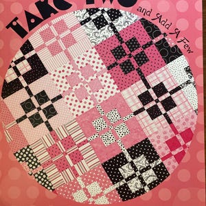 May include: A pink and white quilt pattern design with the text "TAKE TWO and Add A Few" in black. The design features a circular arrangement of various fabric patterns in pink, white, and black. The text "Atkinson Designs" is also visible.