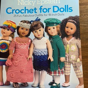 Puede incluir: Un libro titulado Nicky Epstein Crochet for Dolls 25 Fun, Fabulous Outfits for 18-Inch Dolls que muestra cinco muñecas con diversas prendas de ganchillo coloridas, incluyendo sombreros, vestidos, faldas, chaquetas y pantalones en la portada.