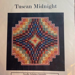 May include: A package featuring a colorful, geometric design titled "Tuscan Midnight." The design is a square pattern with a central diamond shape, using shades of red, blue, orange, and green. The package also includes the text "Needle Delights Originals."