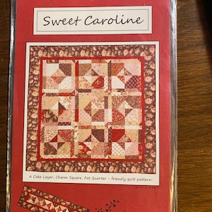 May include: A quilt pattern titled "Sweet Caroline" with a red, brown, and pink floral design. The pattern is for a cake layer, charm square, and fat quarter quilt. The pattern is 69.6 inches by 69.6 inches. The pattern is from Silk Road Creations.