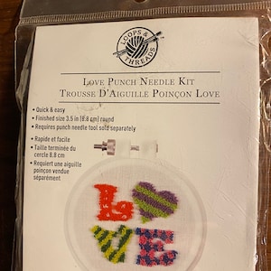 May include: A Love Punch Needle Kit with a white embroidery hoop featuring a colorful 'LOVE' design. The kit includes 3 pieces and requires a punch needle tool sold separately.