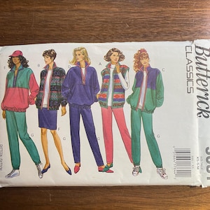 May include: A vintage Butterick Classics sewing pattern featuring illustrations of women's tracksuits. The tracksuits are in various color combinations, including pink, teal, purple, and patterned jackets. The pattern includes sizes XS-S-M.