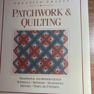 May include: A book titled "PATCHWORK & QUILTING" by HAMLYN CREATIVE CRAFTS. The cover displays a geometric quilt pattern in brown, green, and pink. The text below the image reads: TRADITIONAL AND MODERN QUILTS, MATERIALS, METHODS, TECHNIQUES, HISTORY, TEMPLATE PATTERNS.