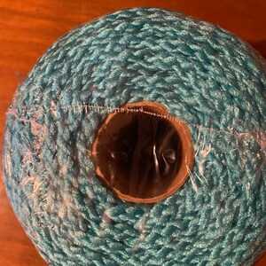 May include: A roll of teal blue rope, wrapped around a cardboard tube, with a clear plastic wrap around the outside.