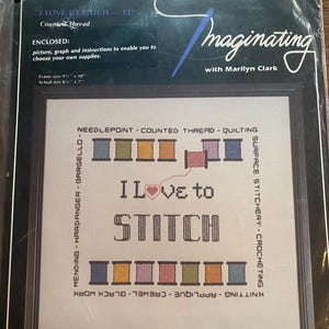 May include: A cross-stitch kit titled "I Love to Stitch" with a framed design. The design features the text "I Love to Stitch" with a heart, surrounded by spools of thread. The kit includes instructions and a graph.