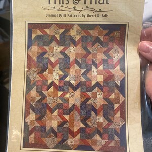 May include: A quilt pattern package from Breakfast Club, titled "This & That." The pattern features a star design in shades of brown, red, and blue. The text reads "Hidden Stars" and "Jelly Roll Friendly."