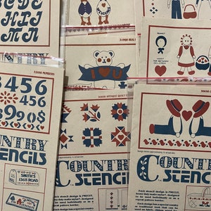 May include: A collection of country-themed stencils featuring various designs, including letters, numbers, geese, hearts, a teddy bear, and a quilt pattern. The stencils are made of mylar and are designed to be used individually or as a repeat pattern border. Each stencil includes a free complimentary counted cross stitch and/or candle wicking pattern.
