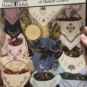 May include: A collection of nine embroidered fabric squares with various designs, including a house, a heart, a tree, and a swan. The squares are displayed in a basket with dried flowers and other decorative elements. The title "A Potpourri of Basket Liners" is displayed at the top of the image.