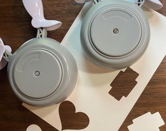 May include: Two gray and white paper punches with a circular design and a white handle. The punches are next to a white piece of paper with heart and rectangle cutouts. The punches have the text "US Patent 7,660..." on them.