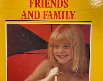 Pode incluir: Um livro amarelo intitulado "Photographing Friends and Family" com um guarda-chuva vermelho e uma menina sorridente na capa. O livro faz parte de "The Kodak Library of Creative Photography".