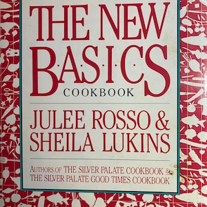 Op de afbeelding: Een kookboek getiteld "THE NEW BASICS COOKBOOK" door Julee Rosso & Sheila Lukins. De omslag heeft een rode achtergrond met witte illustraties van keukengerei en voedsel. De titel staat in grote, vette, rode letters.