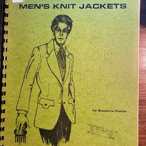 May include: A green book with the title "Sewing Men's Knit Jackets" and a black and white illustration of a man wearing a jacket. The book is by Suzanne Fisher and published by Allstretch Fabrics of Montgomery.