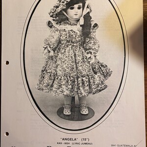May include: A black and white photo of a doll pattern for a 15-inch doll named "Angela". The doll is wearing a white dress with a floral pattern and a white bonnet. The pattern is from Karen Ann's Doll Patterns.