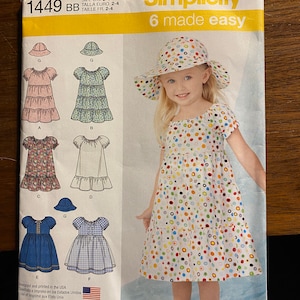 May include: Simplicity sewing pattern number 1449 BB, 6 made easy, for sizes 2-4. The pattern includes instructions for making a dress and a hat. The dress has a variety of styles, including a tiered skirt, a ruffled skirt, and a gingham skirt. The hat is a sun hat with a wide brim.
